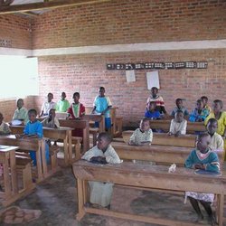 Afrikanische Schüler sitzen auf einfachen Holzbänken in Ihrem Klassenraum